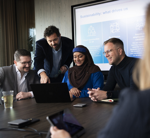 Four RGF Staffing colleagues discussing something in an office meeting room (1)