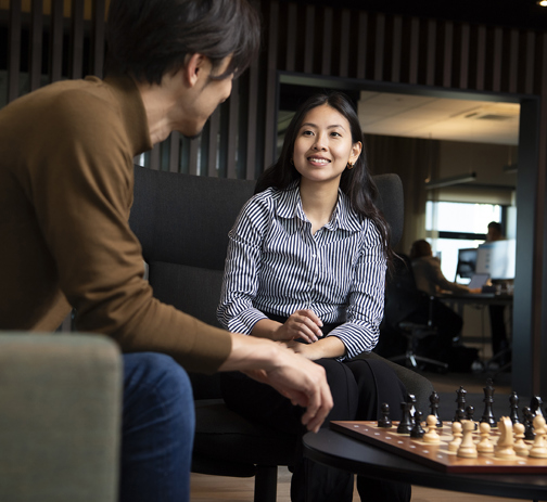 Two colleagues in an office lounge chatting while sitting at a chess table