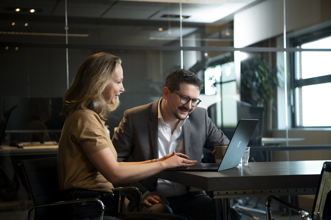 A picture of two colleagues looking at a laptop screen in the office (2)